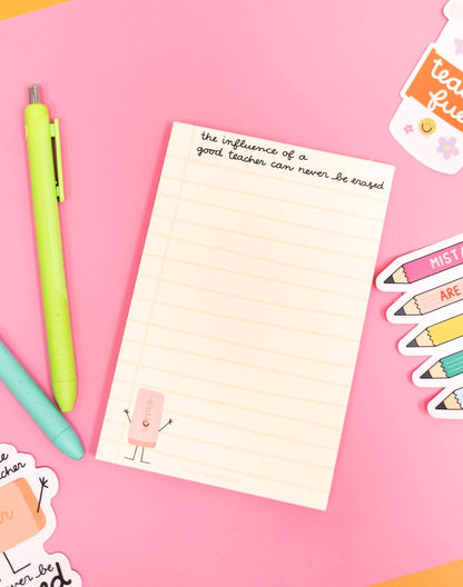 Notepad with motivational quote on a pink background with stationery items