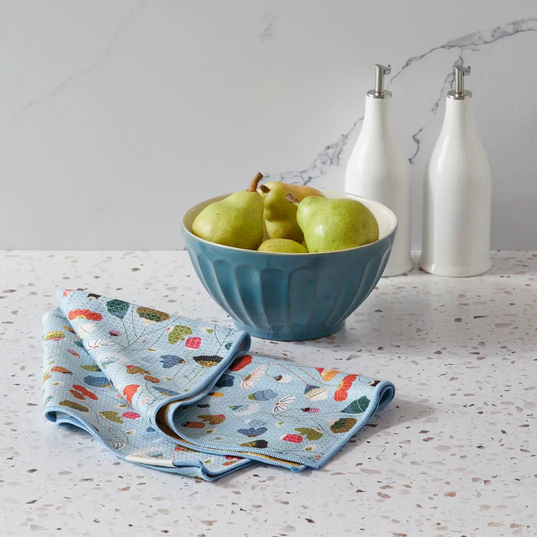 Floral towel draped on a counter top next to a bowl of pears.