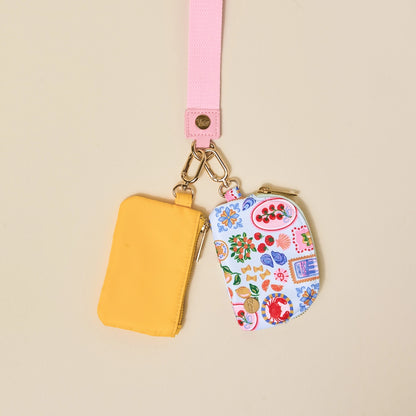 Two small pouches, one yellow and one with a colorful pattern, on a beige background.