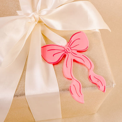 pink flat acrylic bow ornament tied to a package