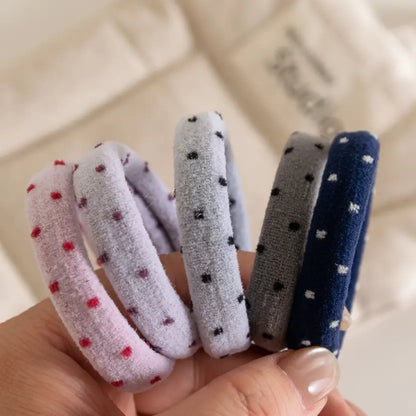person holding 5 assorted polka dot hair ties on their finger