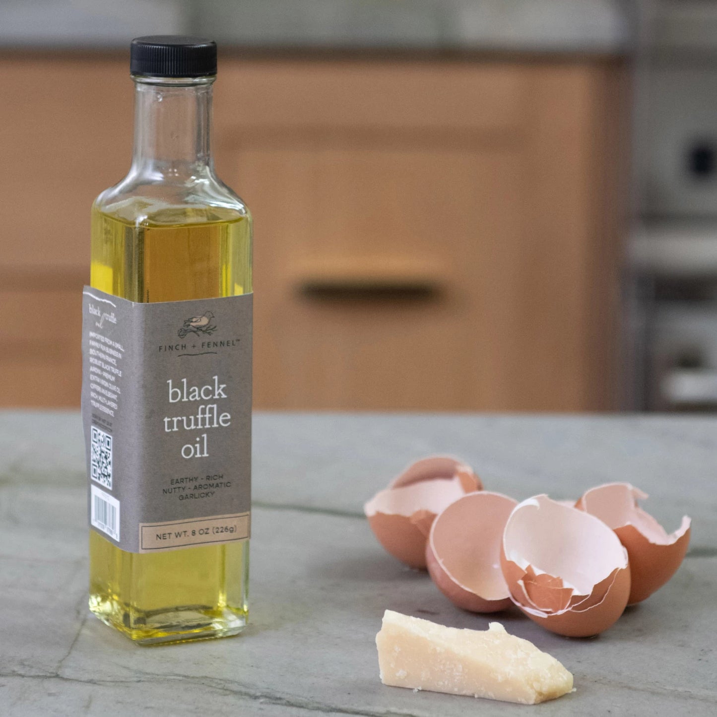 bottle of Black Truffle Oil on a kitchen counter with egg shells and a bit of cheese.