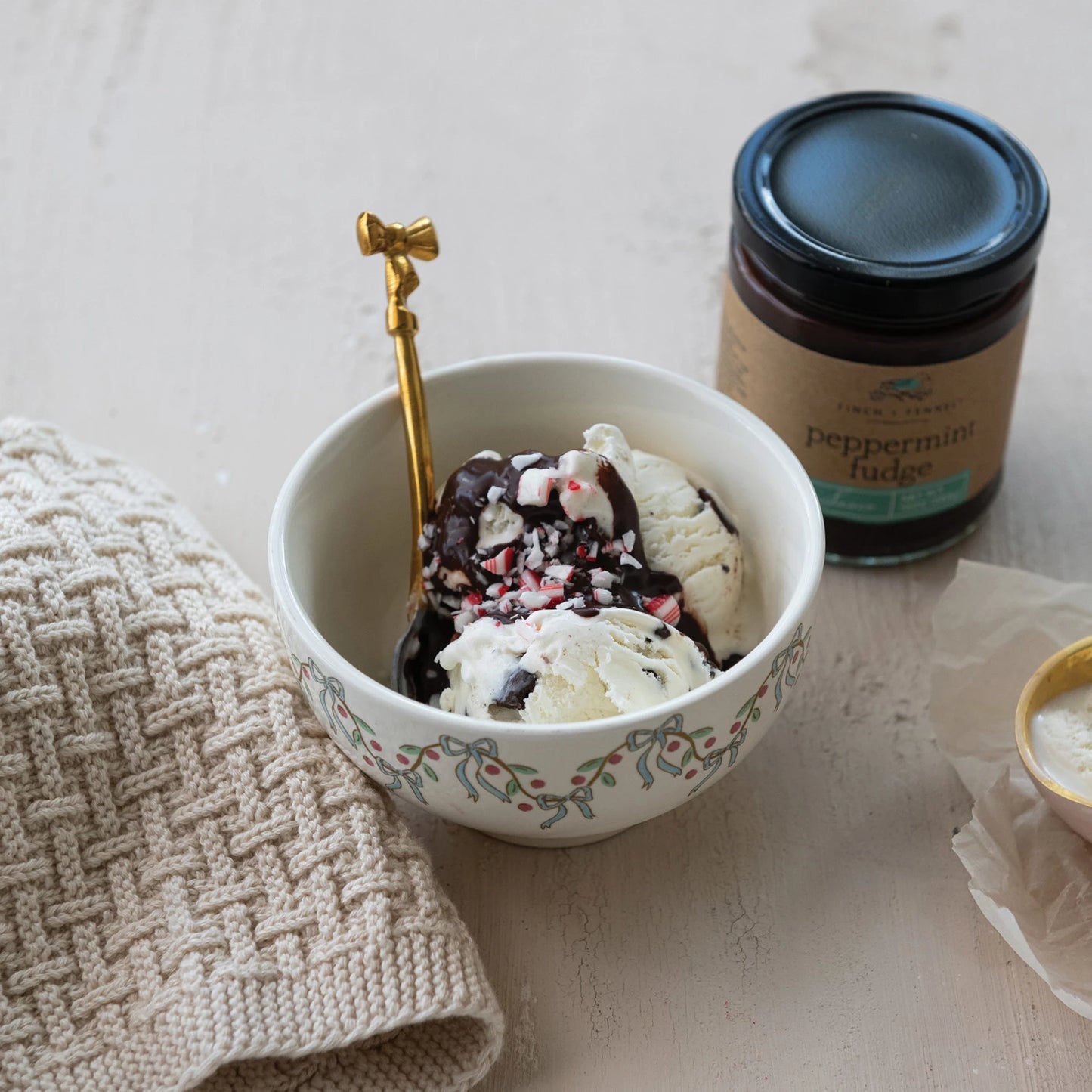 jar of Peppermint Fudge Sauce set next to a bowl of ice cream topped with Peppermint Fudge Sauce
