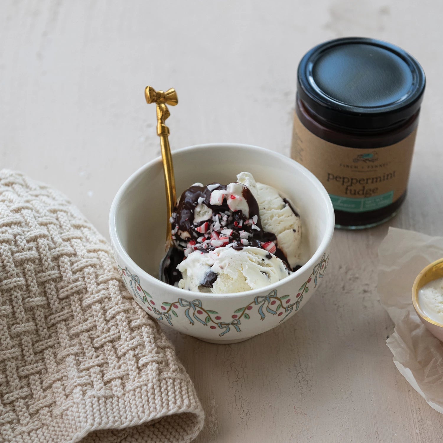 jar of Peppermint Fudge Sauce set next to a bowl of ice cream topped with Peppermint Fudge Sauce