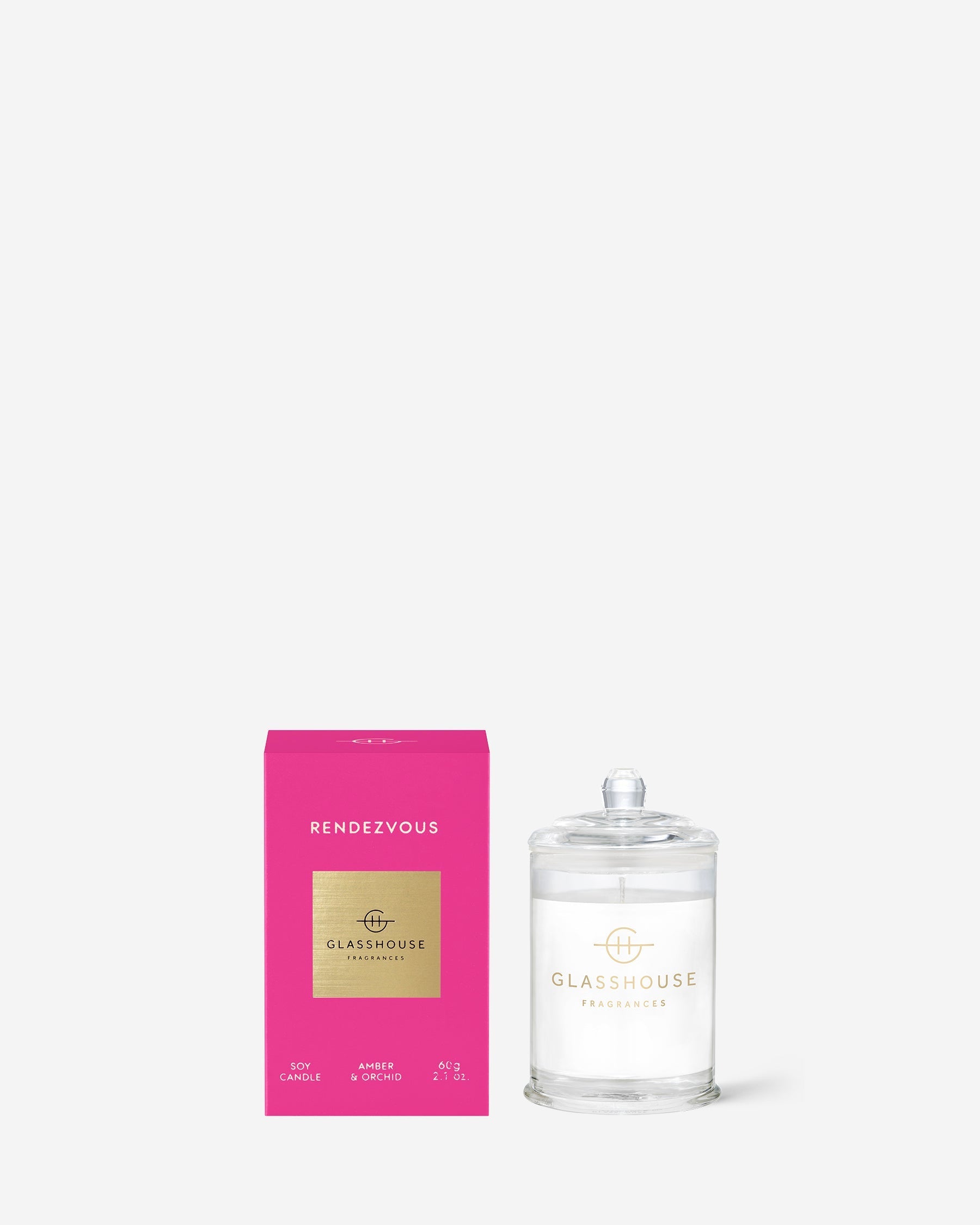  Rendezvous Triple Scented Small Candle in clear glass vessel set next to tis bright pink box