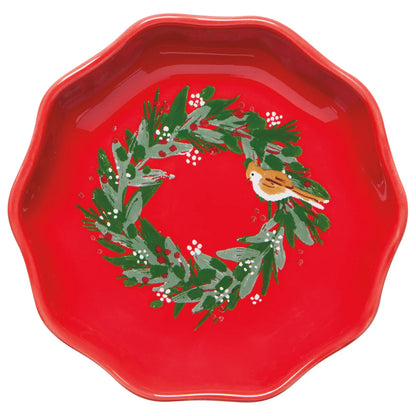 Red dish with wreath printed in the bottom of it, wreath has a little bird perched on it.