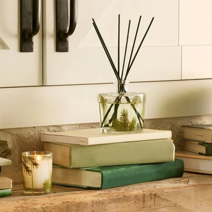 fraisier fir reed diffuser set on a stack of books on a stone counter