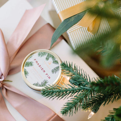 frasier fir travel candle set on a wrapped gift with greenery in the foreground