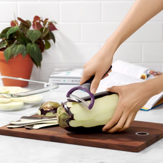 handing holding Good Grips Large Y-Peeler and peeling a potatoe