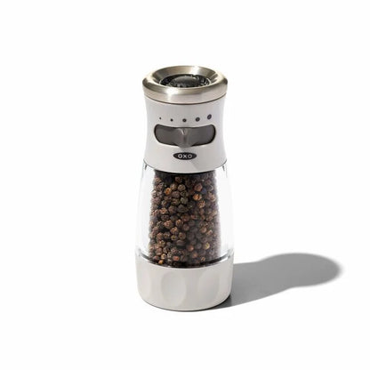 white and clear acrylic pepper grinder filled with pepper corns.