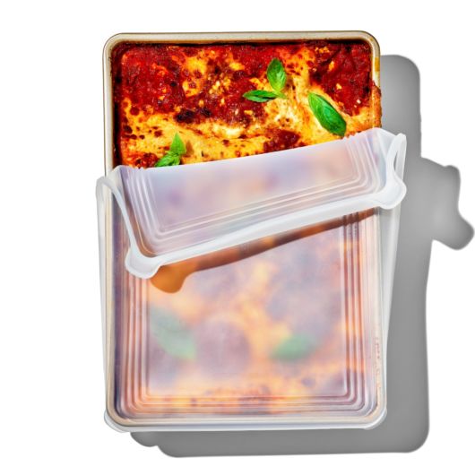 top view of the rectangle Good Grips Silicone Bakeware Lid on a baked lasagna on a white background