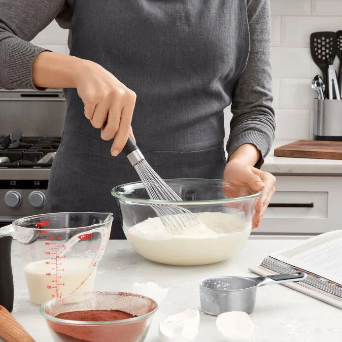 person wearing apron using Good Grips 11" Whisk the mix batter