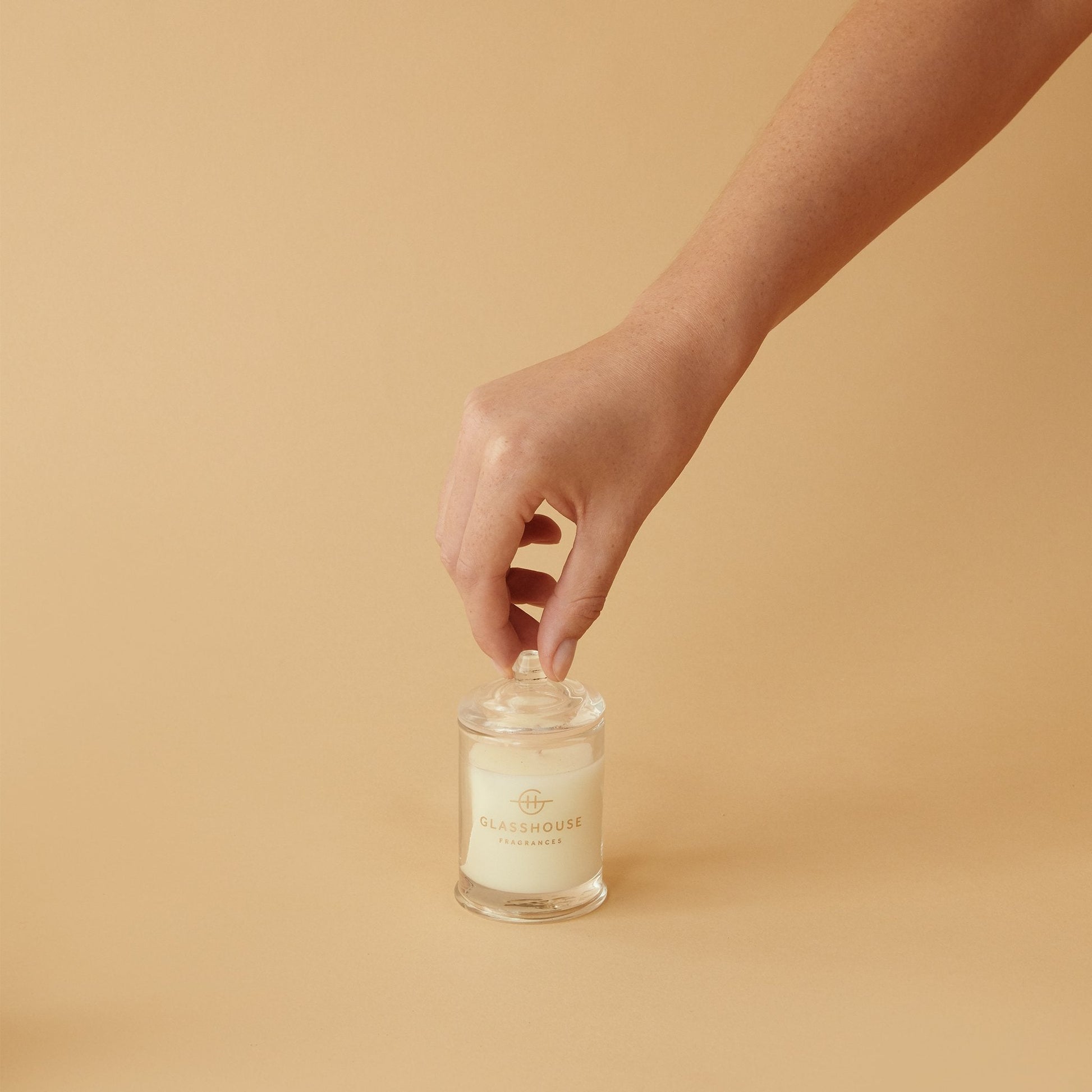 Lost In Amalfi Triple Scented Candle jar displayed against a cream background with a womans hand removing the lid