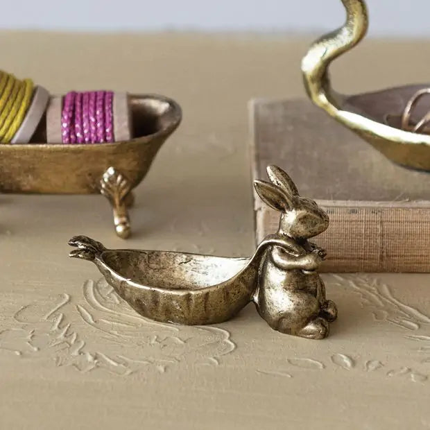 golden rabbit with carrot shaped dish on a textured surface with decorative elements in the background.