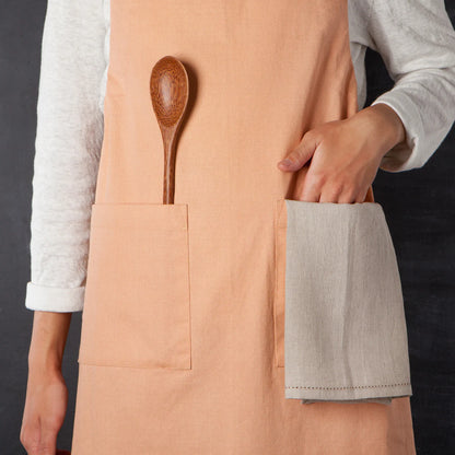 close-up of someonw wearing a nectar apron with their hand and a wooden spoon in the pocket.