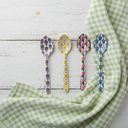 4 assorted small spoons with floral designs arranged on a wooden surface with a green gingham cloth