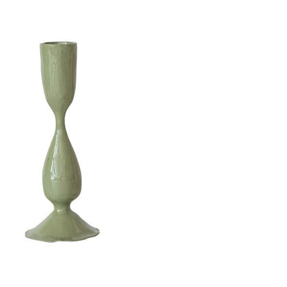 green taper candle holder on a white background