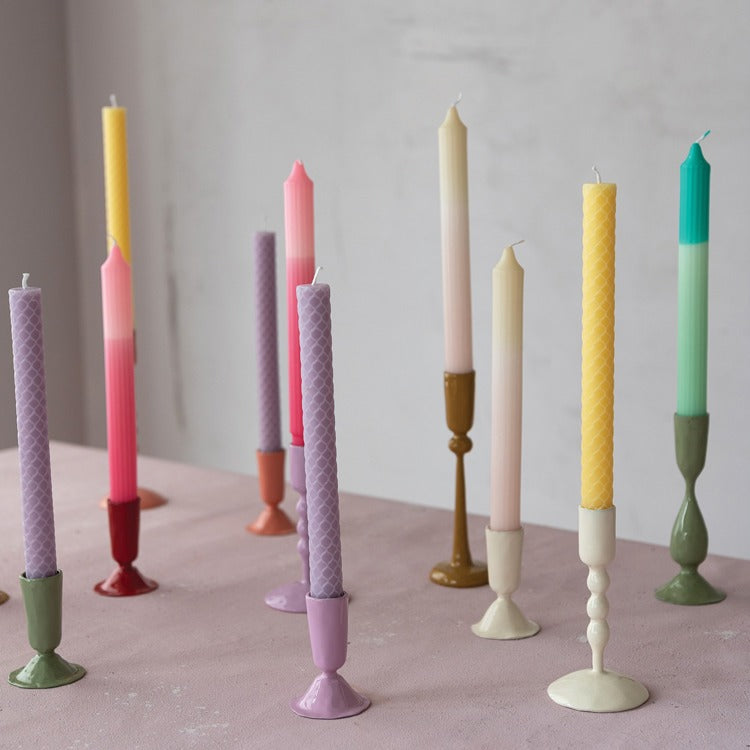 several taper holders holding multi colored candles