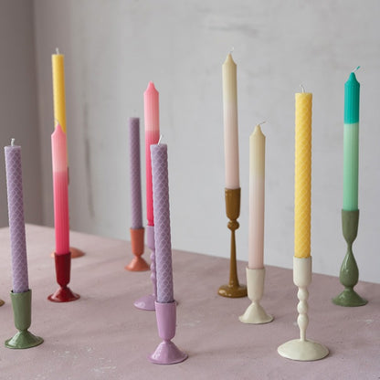 several taper holders holding multi colored candles
