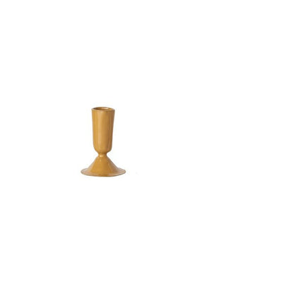 small mustard colored taper candle holder on a white background