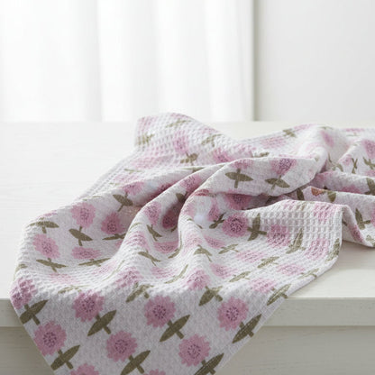 white tea towel with pink flowers and green leaves draped over a white wooden table