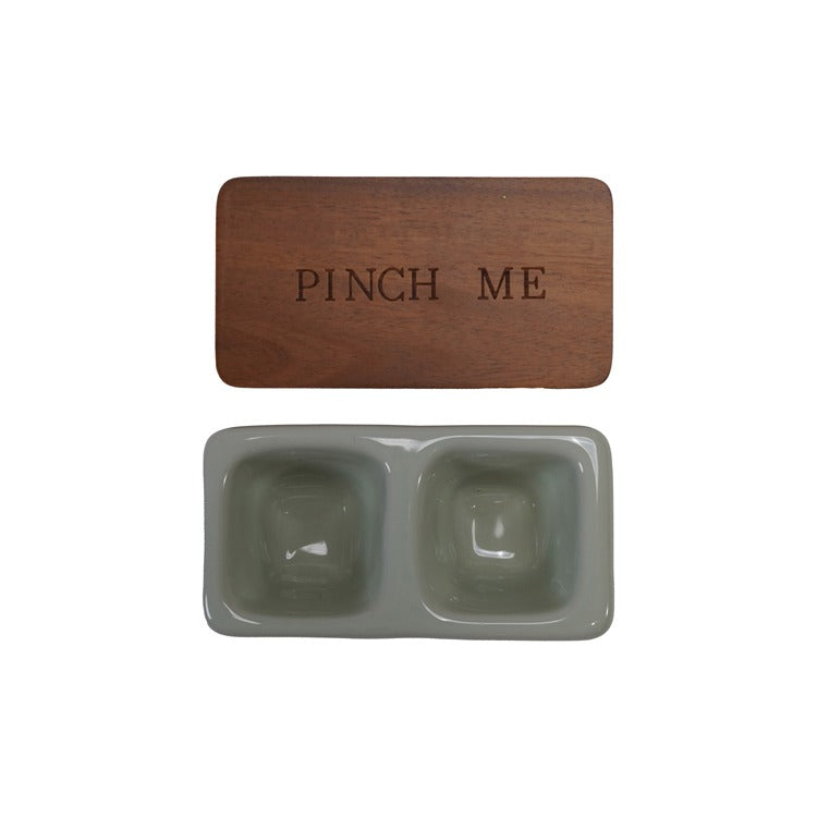 wood lid with engraved phrase "pinch me" above a greyish taupe ceramic dish with two salt wells