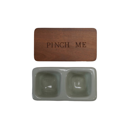 wood lid with engraved phrase "pinch me" above a greyish taupe ceramic dish with two salt wells