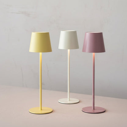 Three desk  lamps in yellow, white, and pink with colored shades on a neutral background.