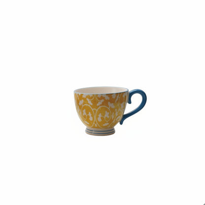 Ceramic mug with white and mustard pattern floral pattern on the outside and a teal handle
