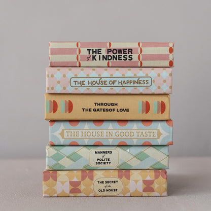 Stack of books with decorative covers on a neutral background