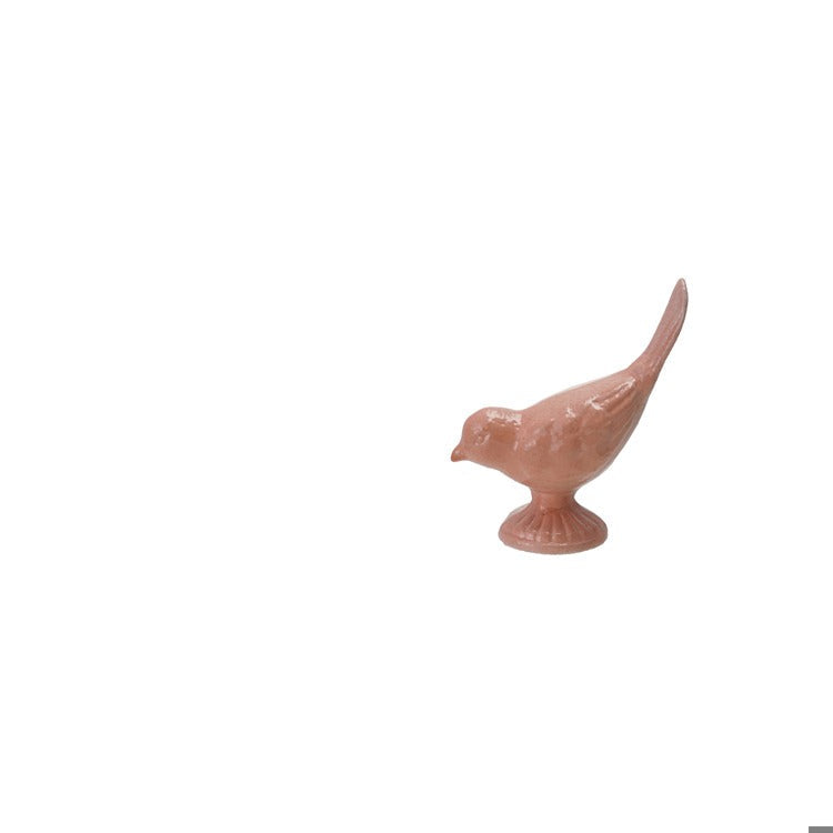 pink metal bird figurine with its head down and tail up