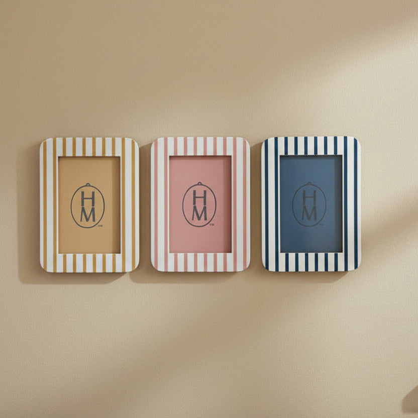white and yellow striped frame next to a pink and white striped frame next to a blue and white striped frame hung on a beige wall