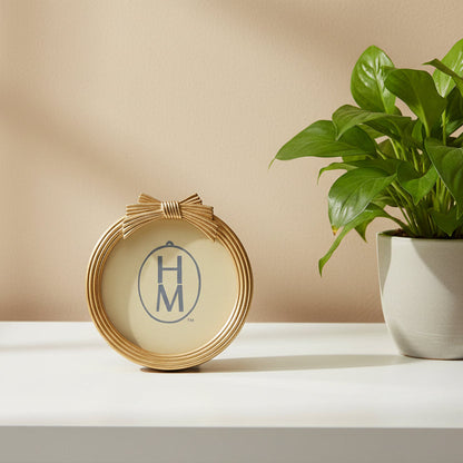 gold round frame with bow on the top of the frame set on a table with a house plant
