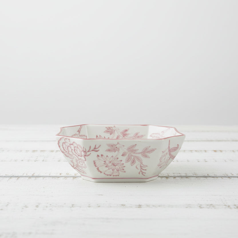 white bowl with pink floral design set on a wooden surface