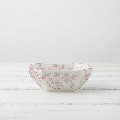 white bowl with pink floral design set on a wooden surface
