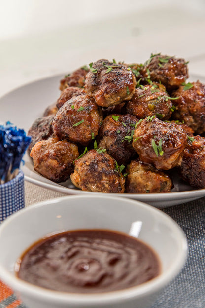 meatballs on a plate and a bowl of Henry Bain's Pendennis Club Sauce on a table with toothpicks.