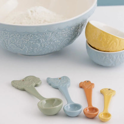 Set of colorful measuring spoons with decorative bowls in the background.