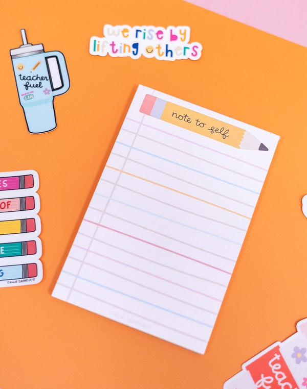 Notepad with pencil design on an orange background with stickers around it
