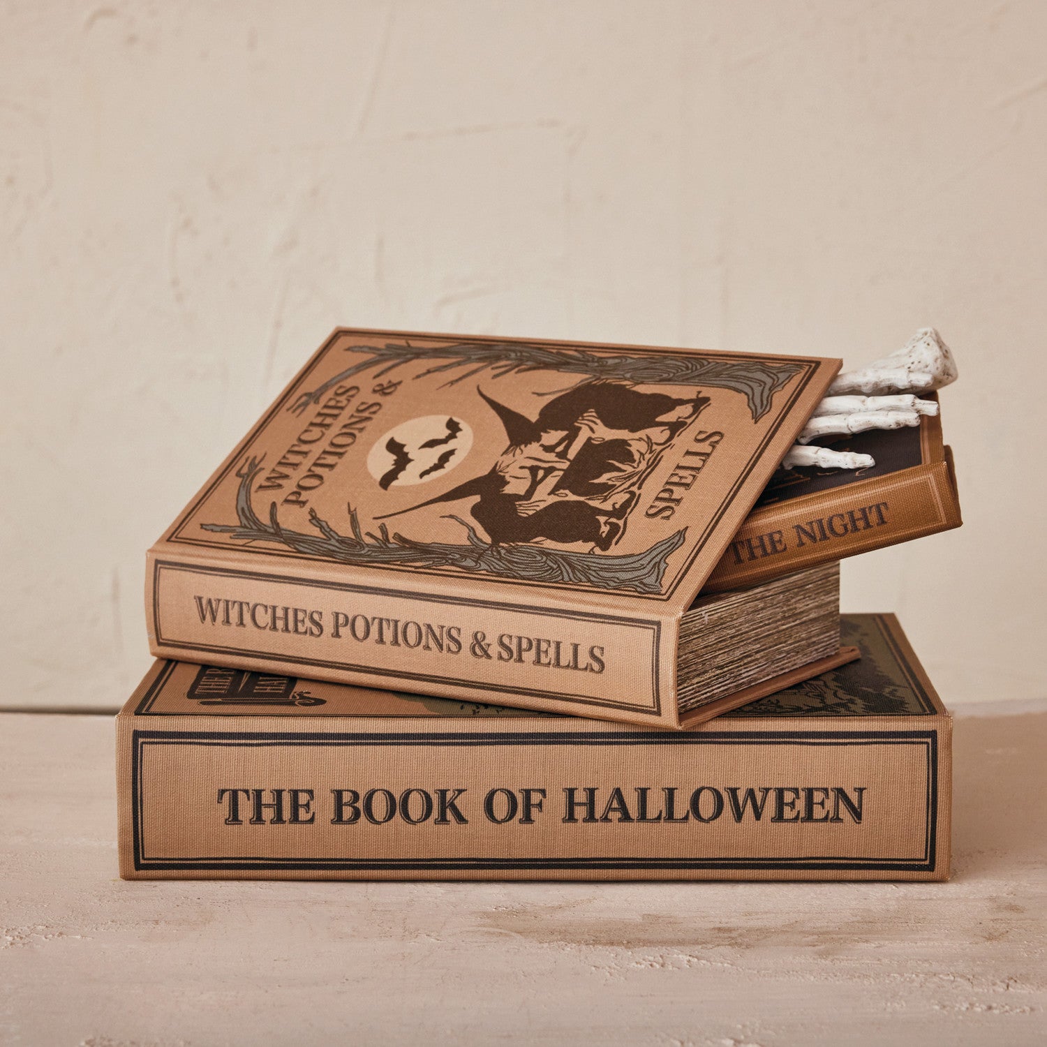 3 book boxes stacked, one is slightly open with a skeleton hand inside