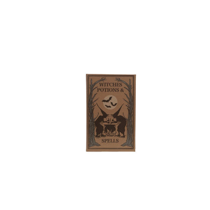 light brown book box with black and pale green image of witches and trees with book title "witches potions & spells"