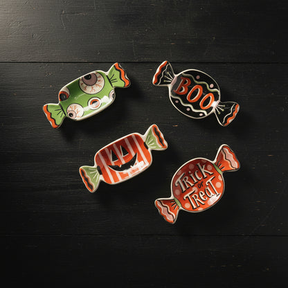 4 halloween candy dishes on a black wooden surface