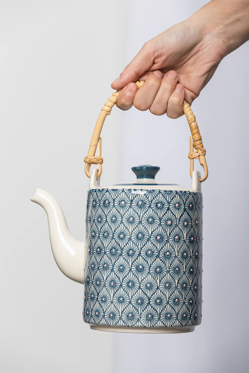 hand holding decorative teapot by the handle