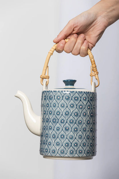 hand holding decorative teapot by the handle