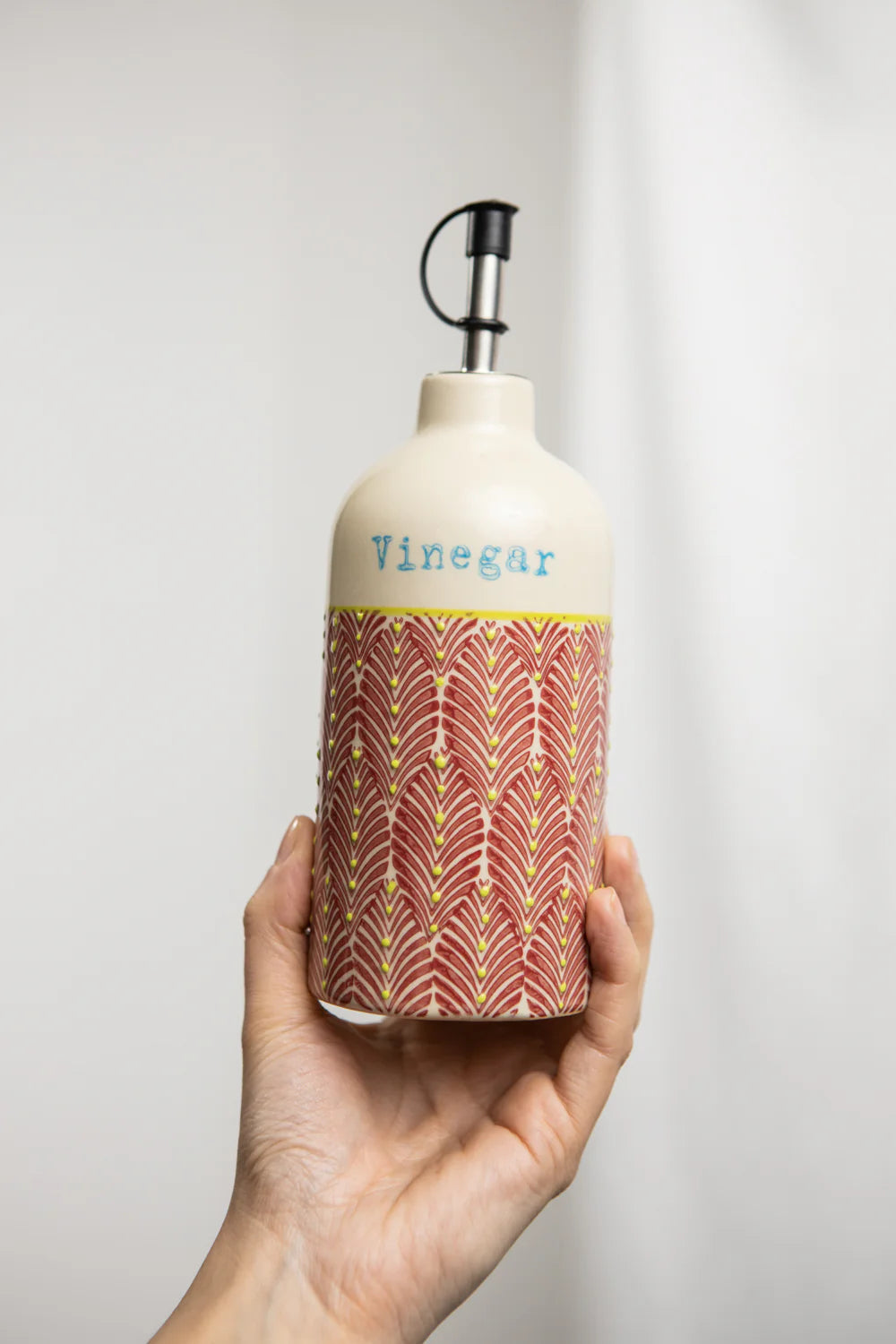 Hand holding a bottle labeled 'Vinegar' with decorative design