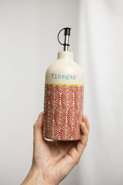 Hand holding a bottle labeled 'Vinegar' with decorative design