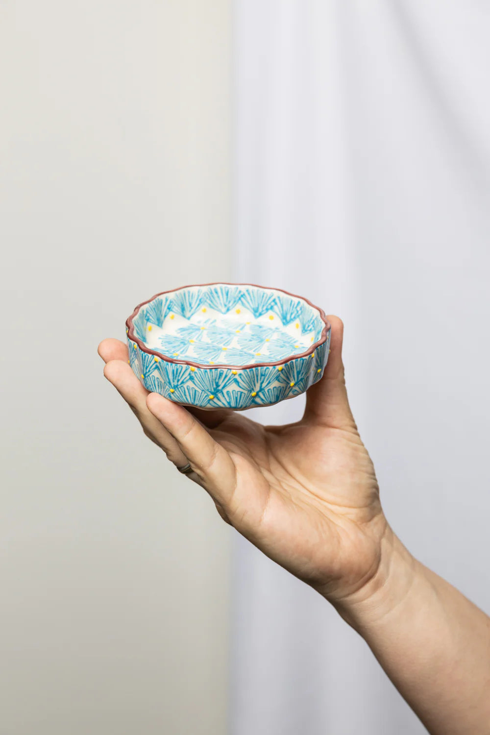 hand holding Blue Art Deco Tartelette Dish in front of a light grey background