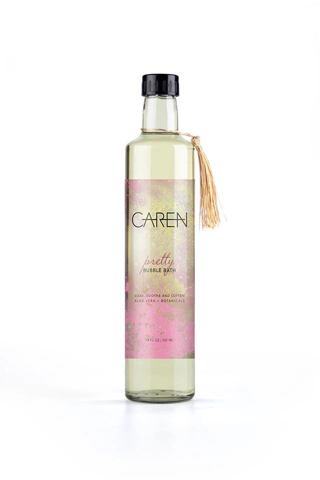 glass bottle with tassel around the neck and a  pink and gold label filled with pretty bubble bath.