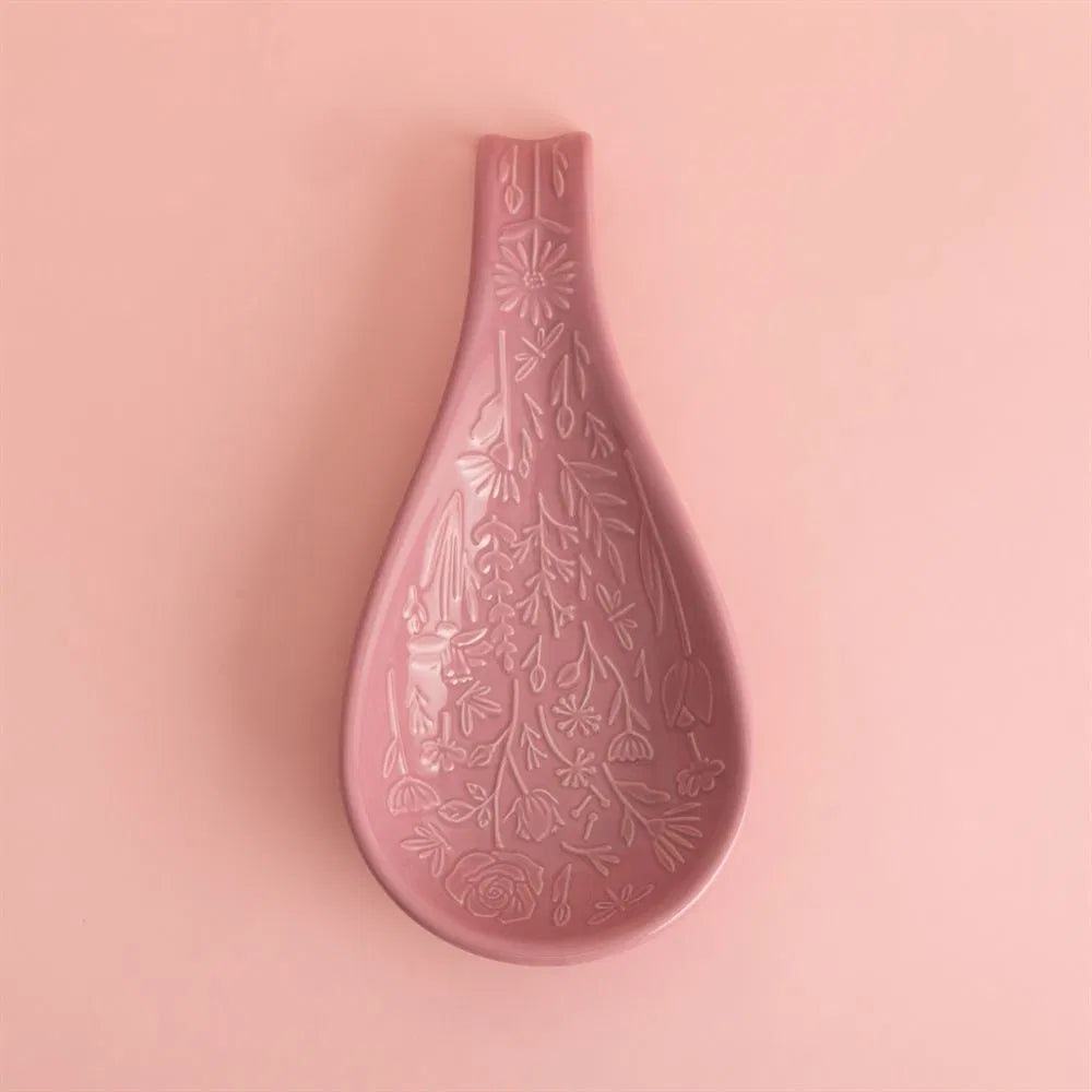 Pink ceramic spoon rest with floral patterns on a pink background