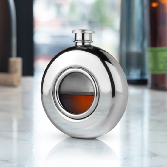 A stainless steel flask with a glass porthole window, displayed on a marble surface.