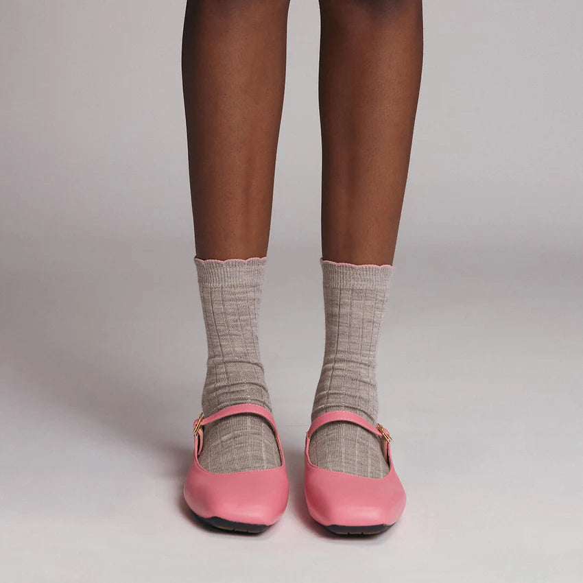 Pink shoes worn with gray socks on a neutral background